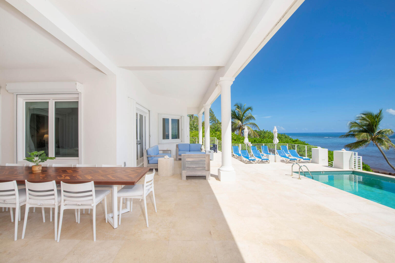 The veranda features an alfresco dining table and plush outdoor furniture. 