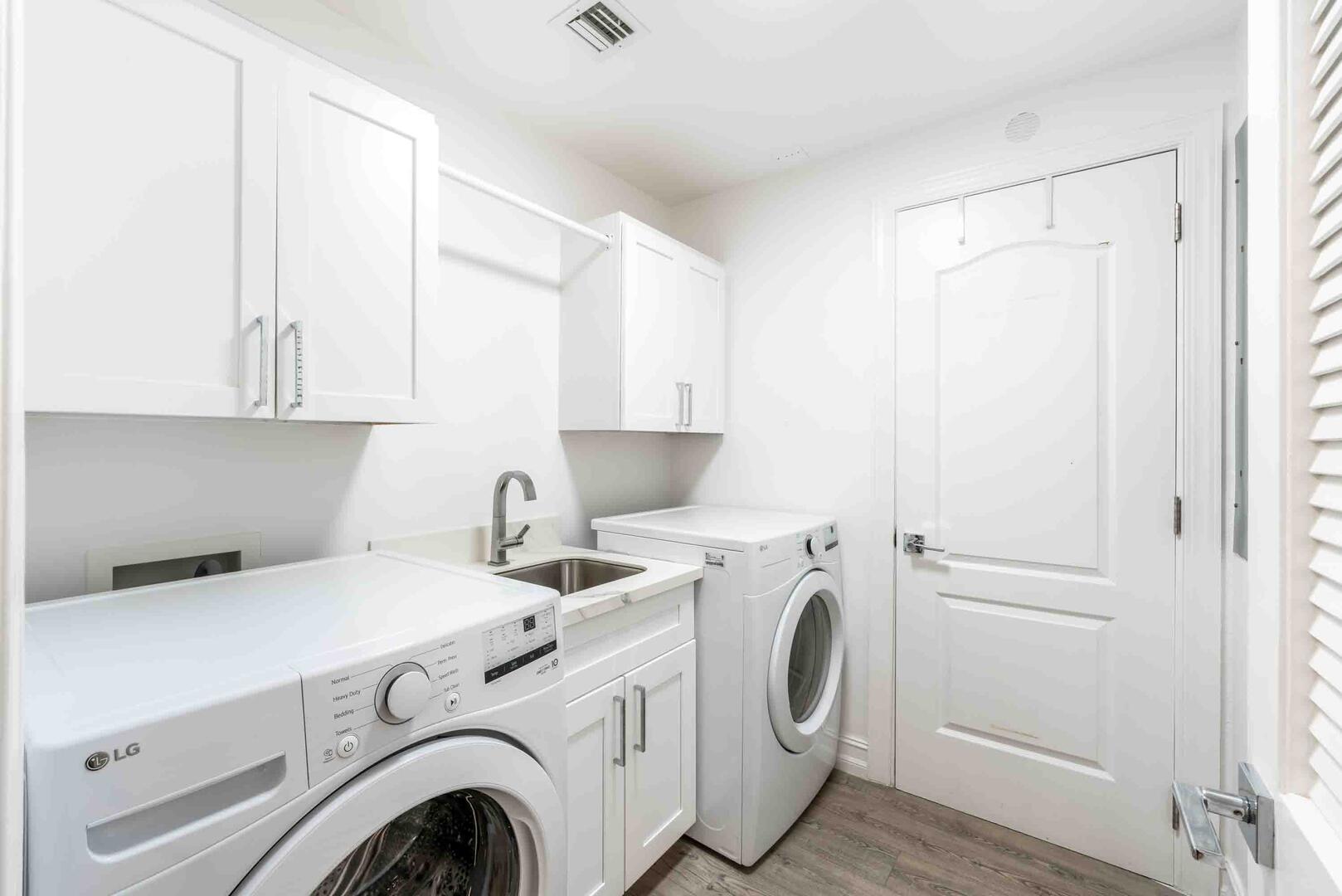 In-unit laundry room with washer, dryer, and utility sink. 